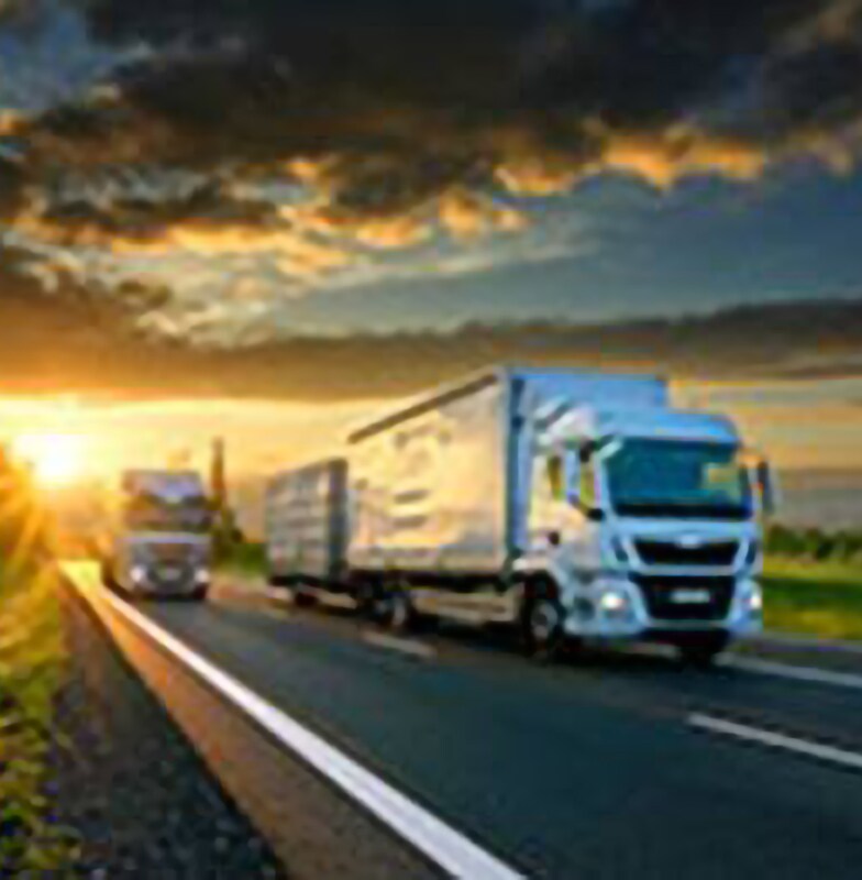 Two trucks on a highway during sunset