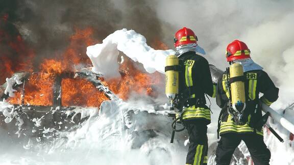 Firefighters in uniform dousing a flame
