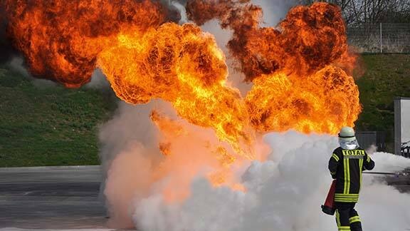 Firefighter in suit dousing a flame in an outdoor space