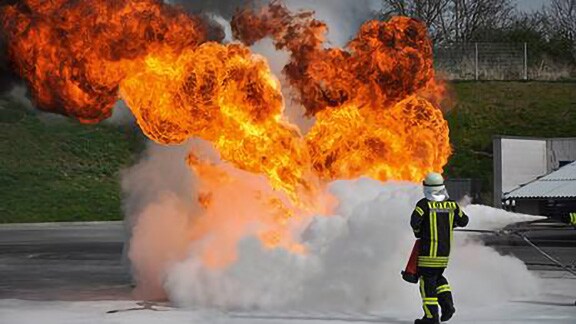 Firefighter in uniform dousing a flame