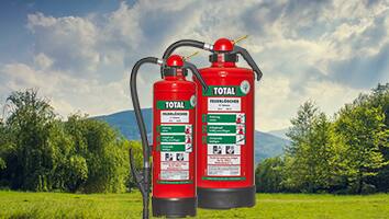 Two fire extinguishers of the brand TOTAL overlaid on shot of the green countryside