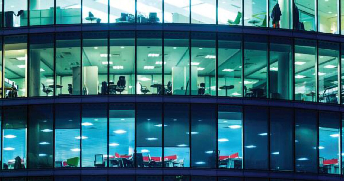 Glass office building lit up at night-time