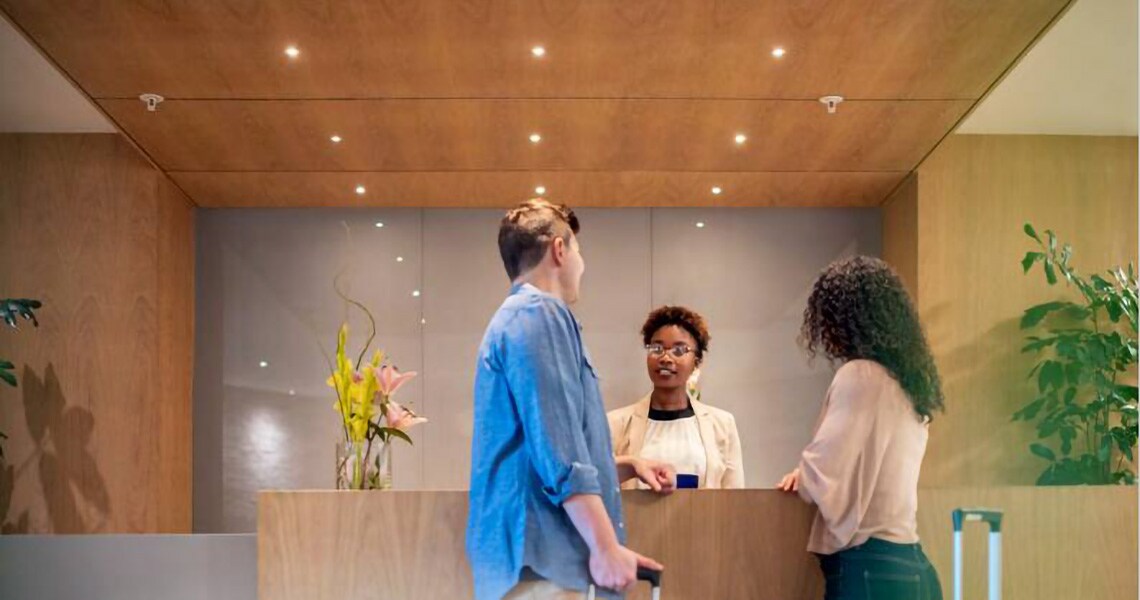 A man and a woman talking to a female manager in a hotel lobby