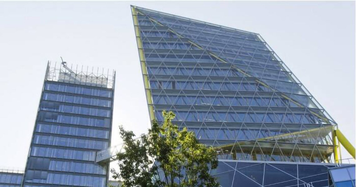 Modern commercial buildings with glass exteriors surrounded by greenery