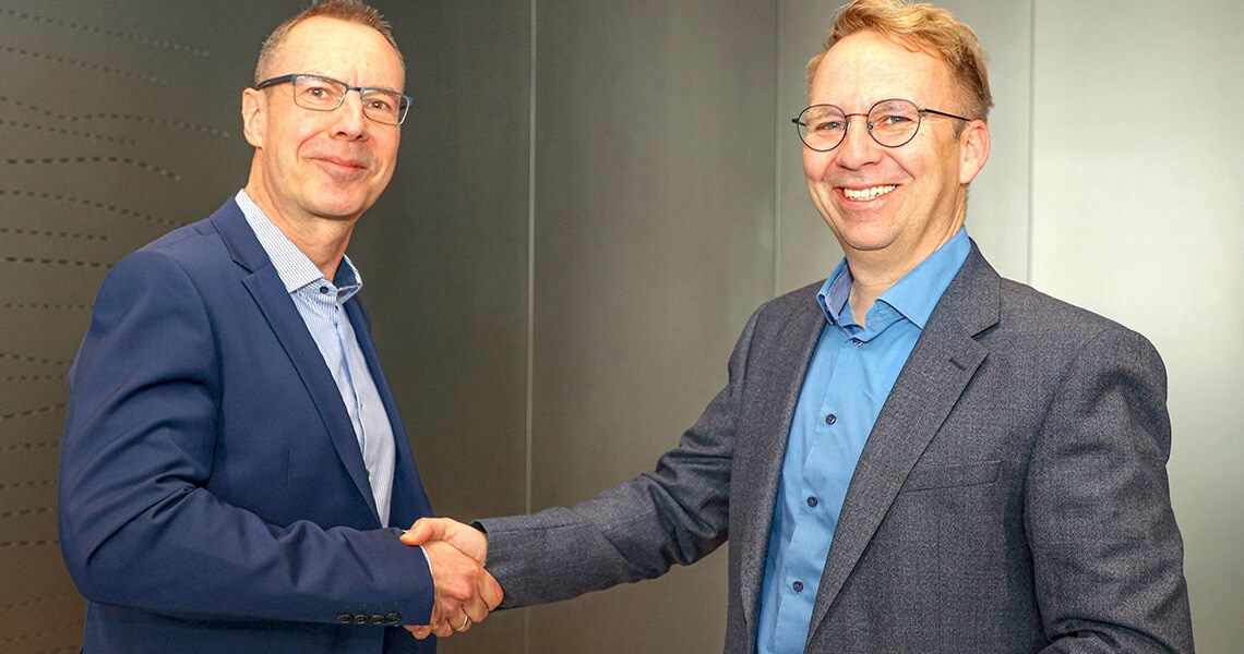 Two men shaking hands and smiling at the camera