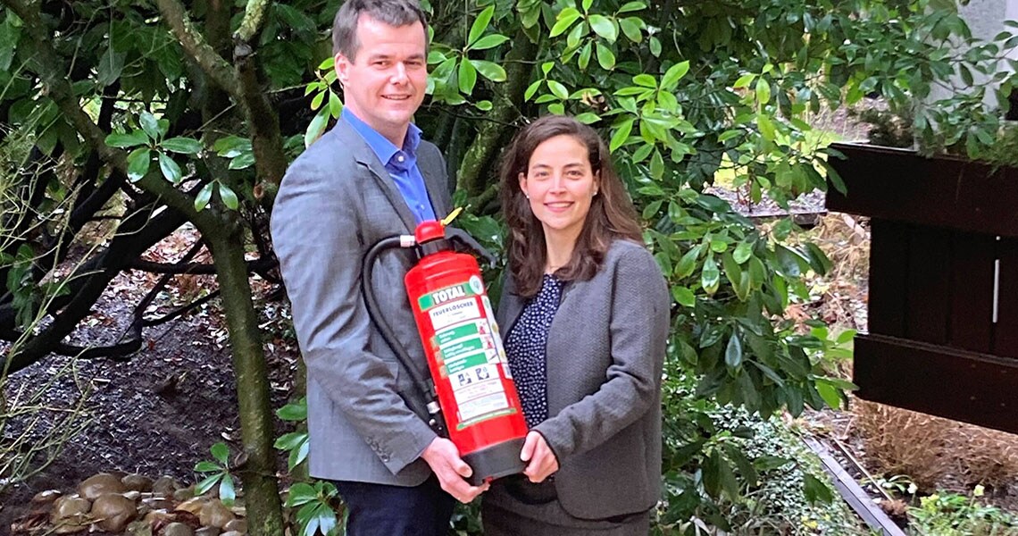 Two people holding a Total fire extinguisher