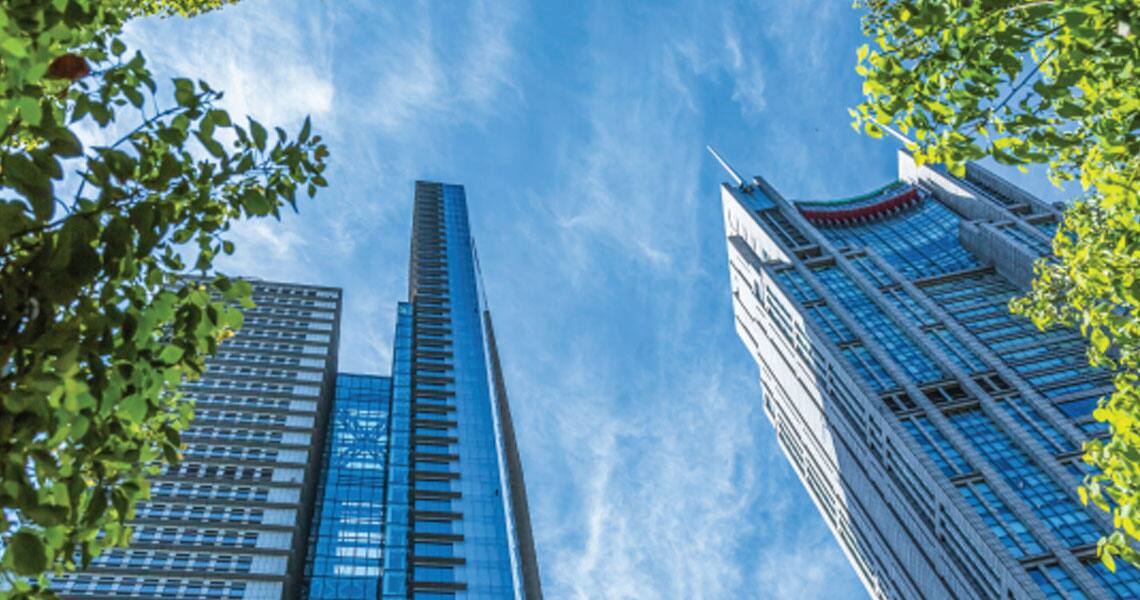 Low-angle shot of high-rise commercial buildings surrounded by trees