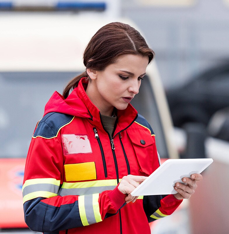 A paramedic working on a tablet in front of an ambulance