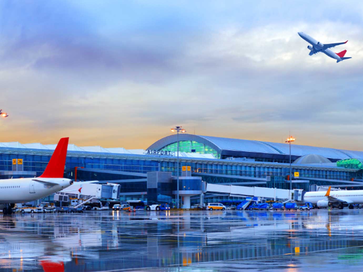 A flight taking off above an airport tarmac dampened by the rain