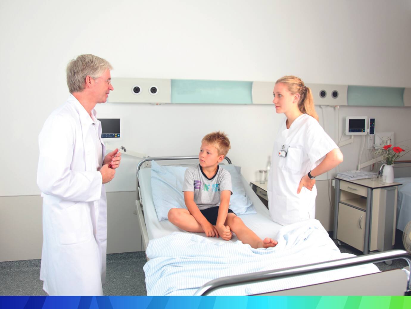 A doctor and a nurse having a conversation with a patient seated on the bed