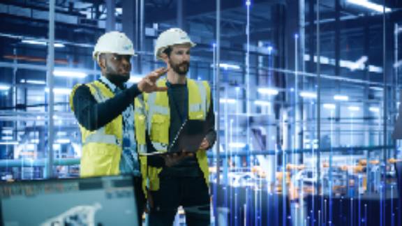 Two mechanics in a factory, while one of them points at something